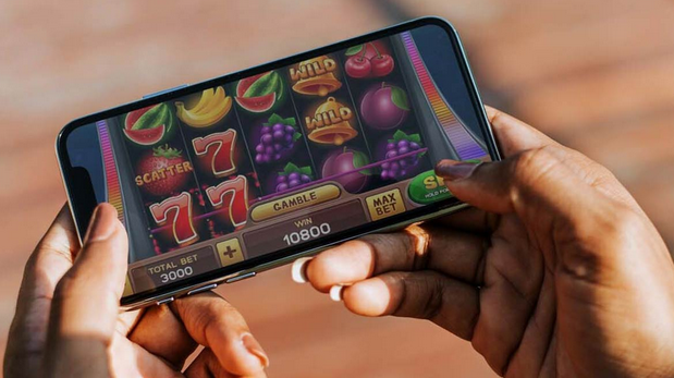 two hands holding a mobile phone showing slot games